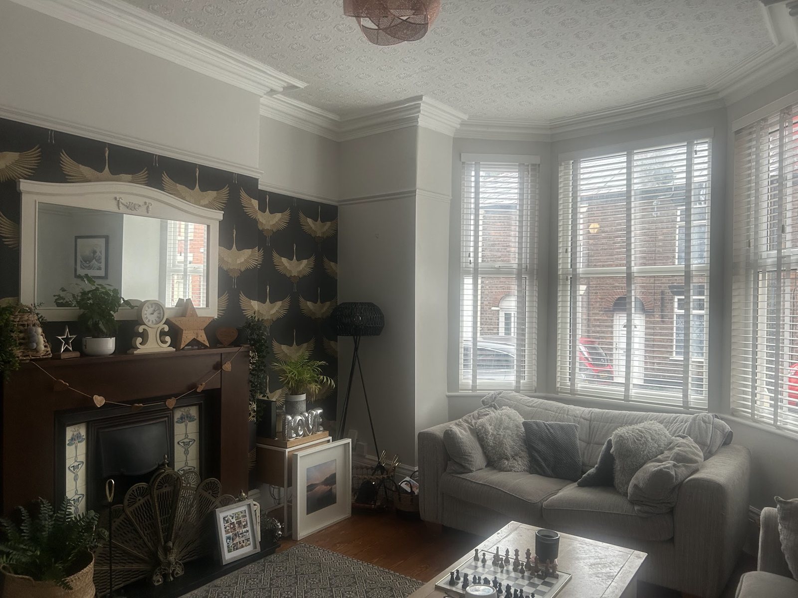 A front room with a bay window and a crane-print feature wallpaper