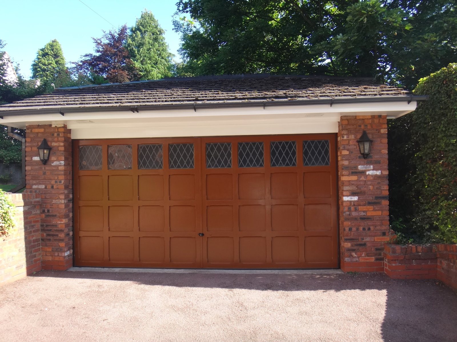 A freshly painted wooden double garage door between brick piers