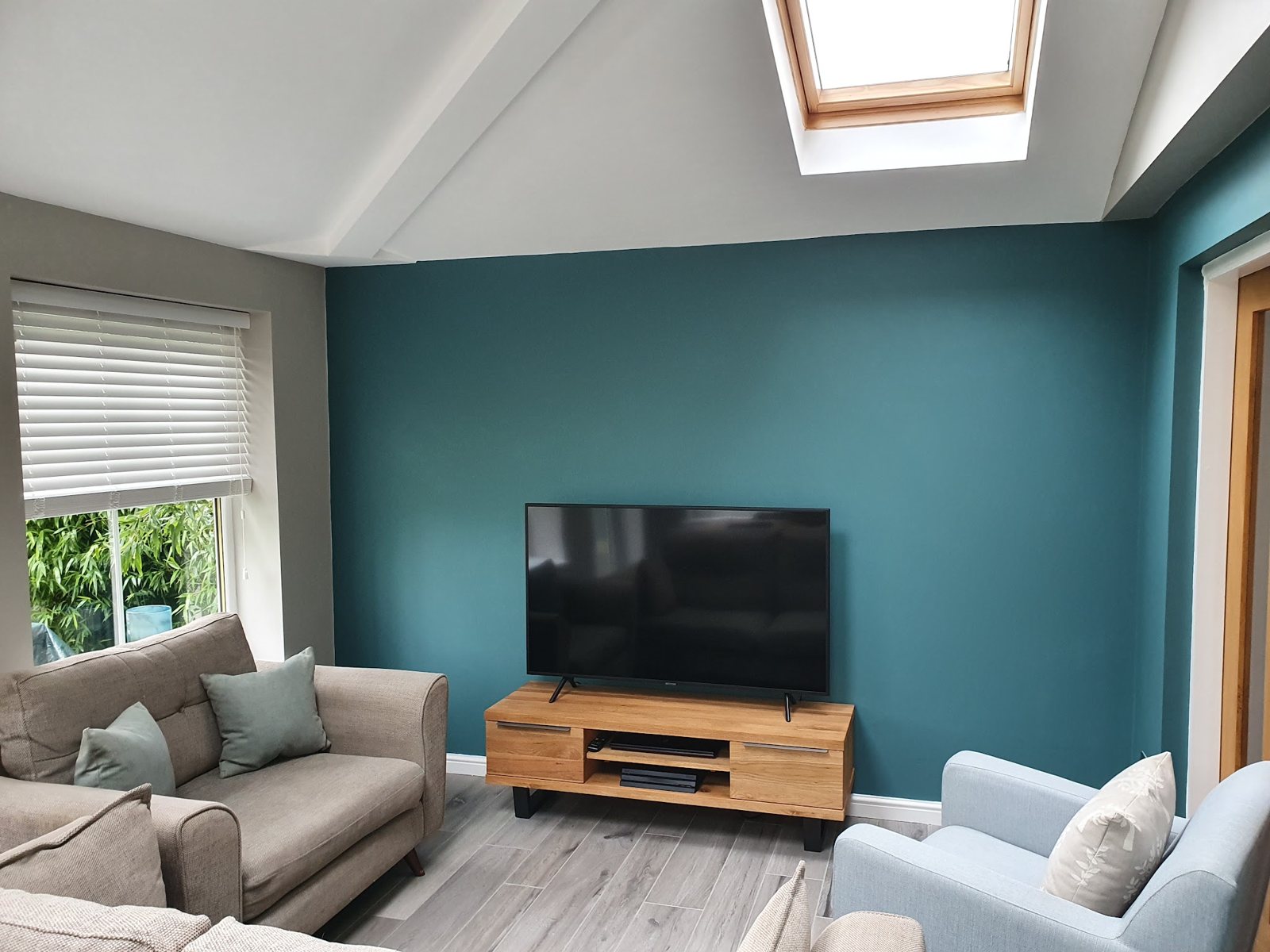 A living room with a deep teal feature wall under a vaulted ceiling