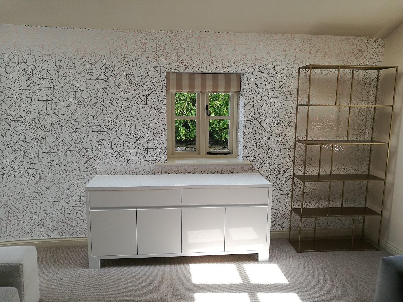 A sitting room papered in a fine grey line-pattern wallpaper