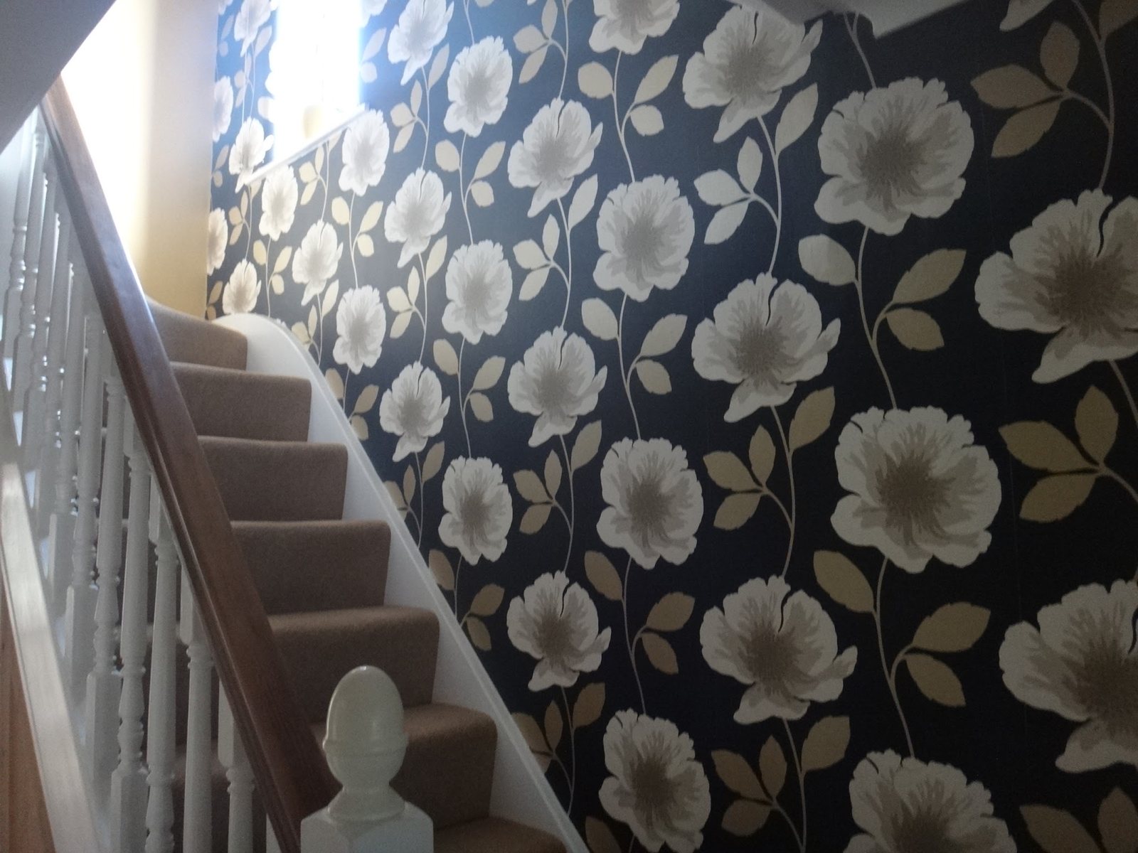 A stairwell hung with a large black and cream floral wallpaper